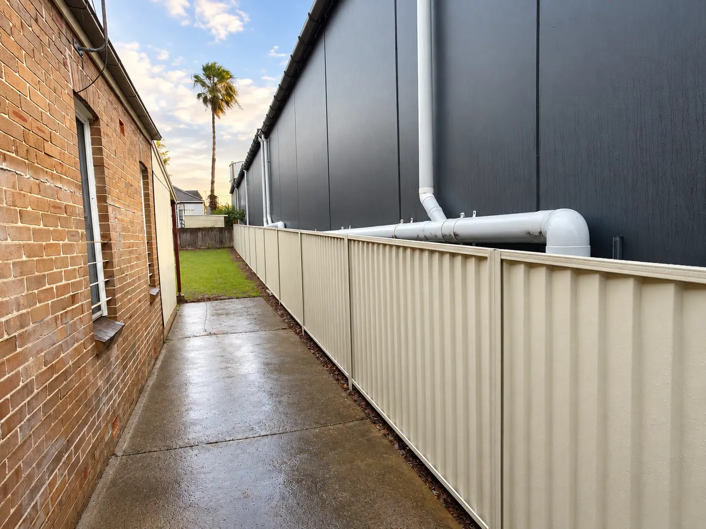 Long cream Colorbond fence installed between residential buildings
